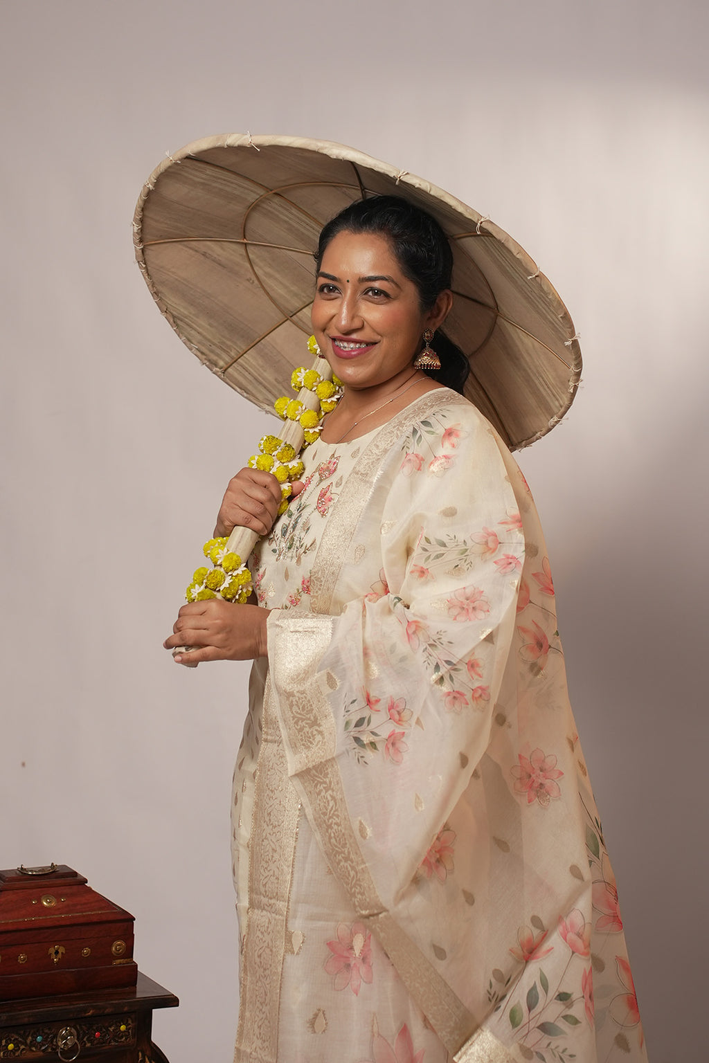 Woman in Aroha Blush Petals co-ord set looking away, holding a traditional Onam olakkuda umbrella
