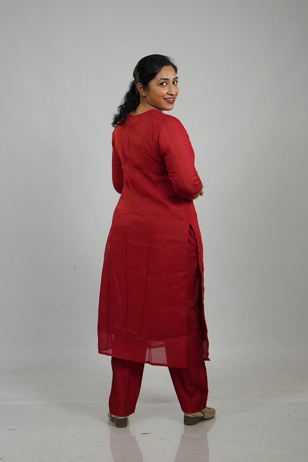 Woman in Aroha Crimson Muse red co-ord set posing with an over the shoulder look