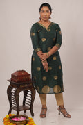 Woman in Aroha Emerald Grace co-ord set standing with arms crossed amid Onam festive decor