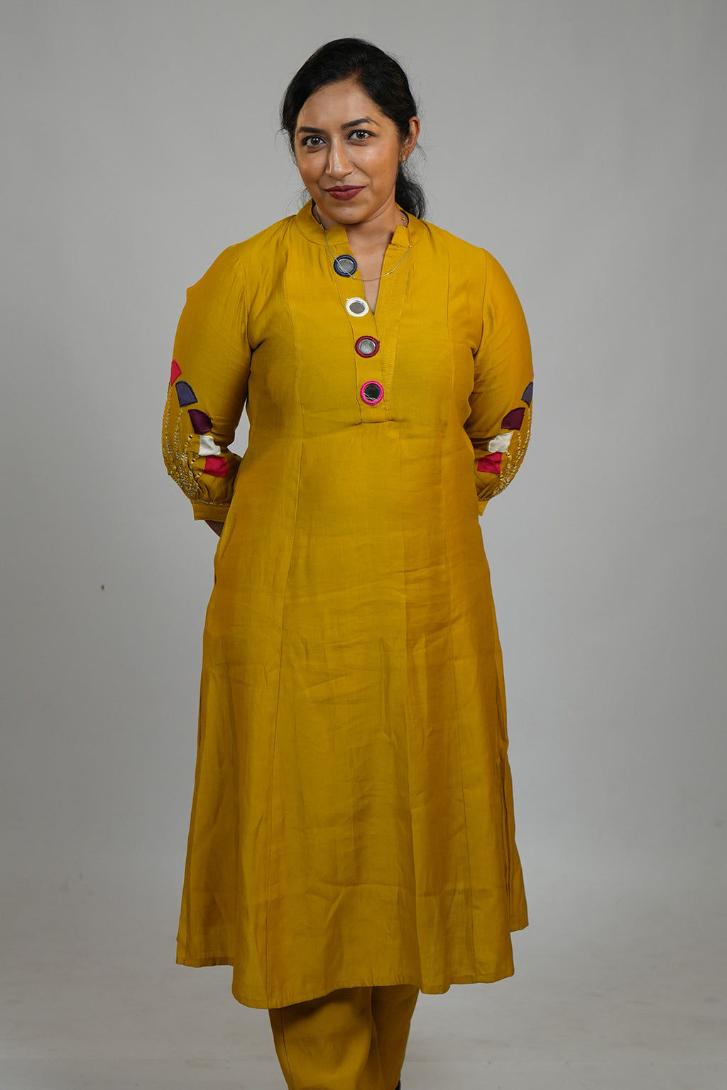 Woman in Aroha Mustard Muse co-ord set standing with hands clasped behind her back