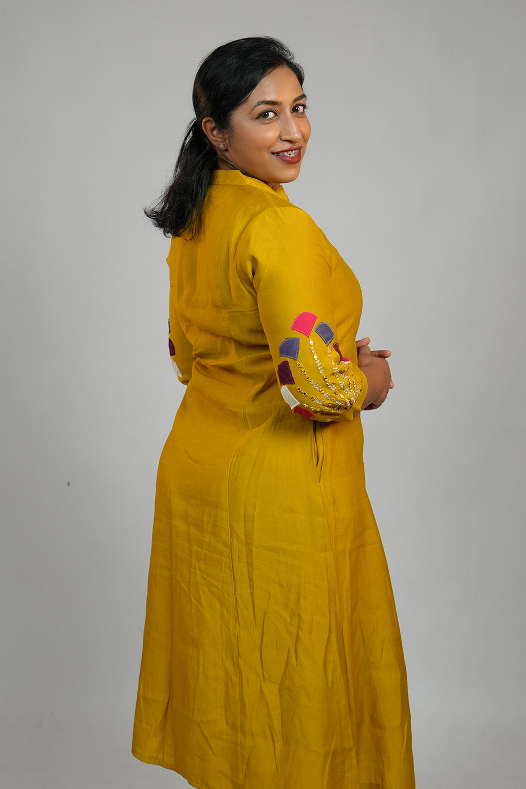 Woman in Aroha Mustard Muse co-ord set posing with an over the shoulder look