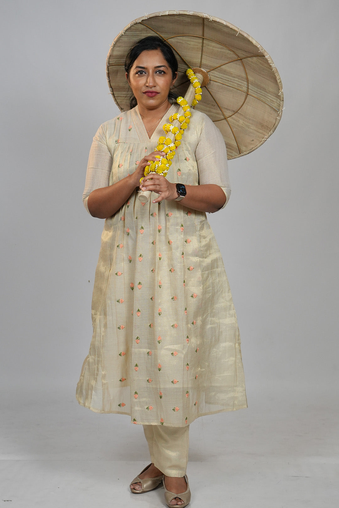 Woman standing in Aroha Peach Whisper co-ord set, holding a traditional Onam olakkuda umbrella