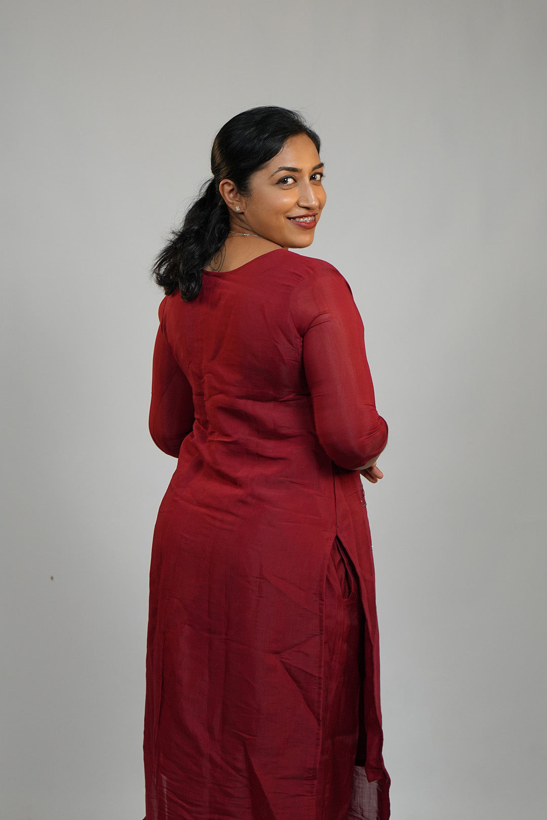 Woman in Aroha Ruby Grace maroon co-ord set posing with an over the shoulder look